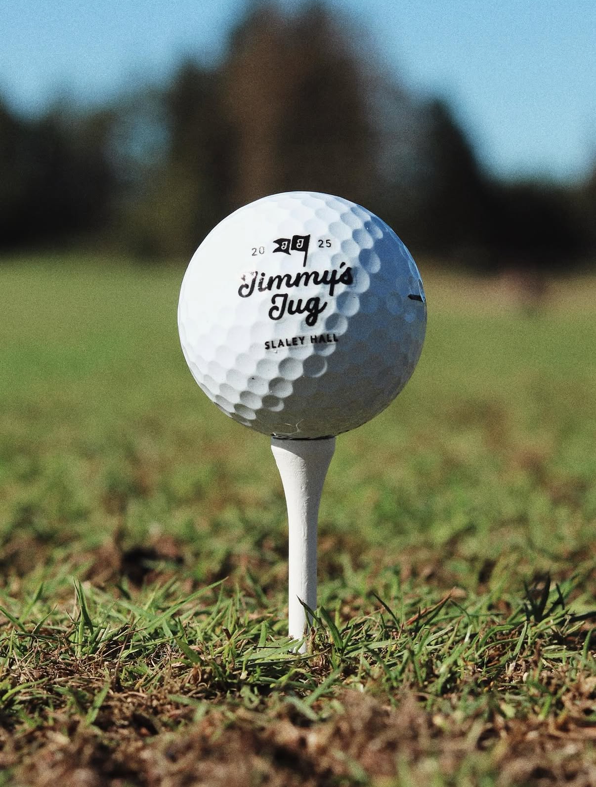 A Jimmy's Jug branded golf ball teed up on the fairway